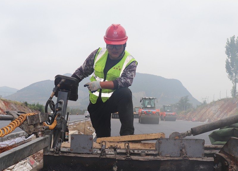 4、油層施工隊長朱紹濤根據(jù)現(xiàn)場實際微調(diào)攤鋪機控制攤鋪質量_副本